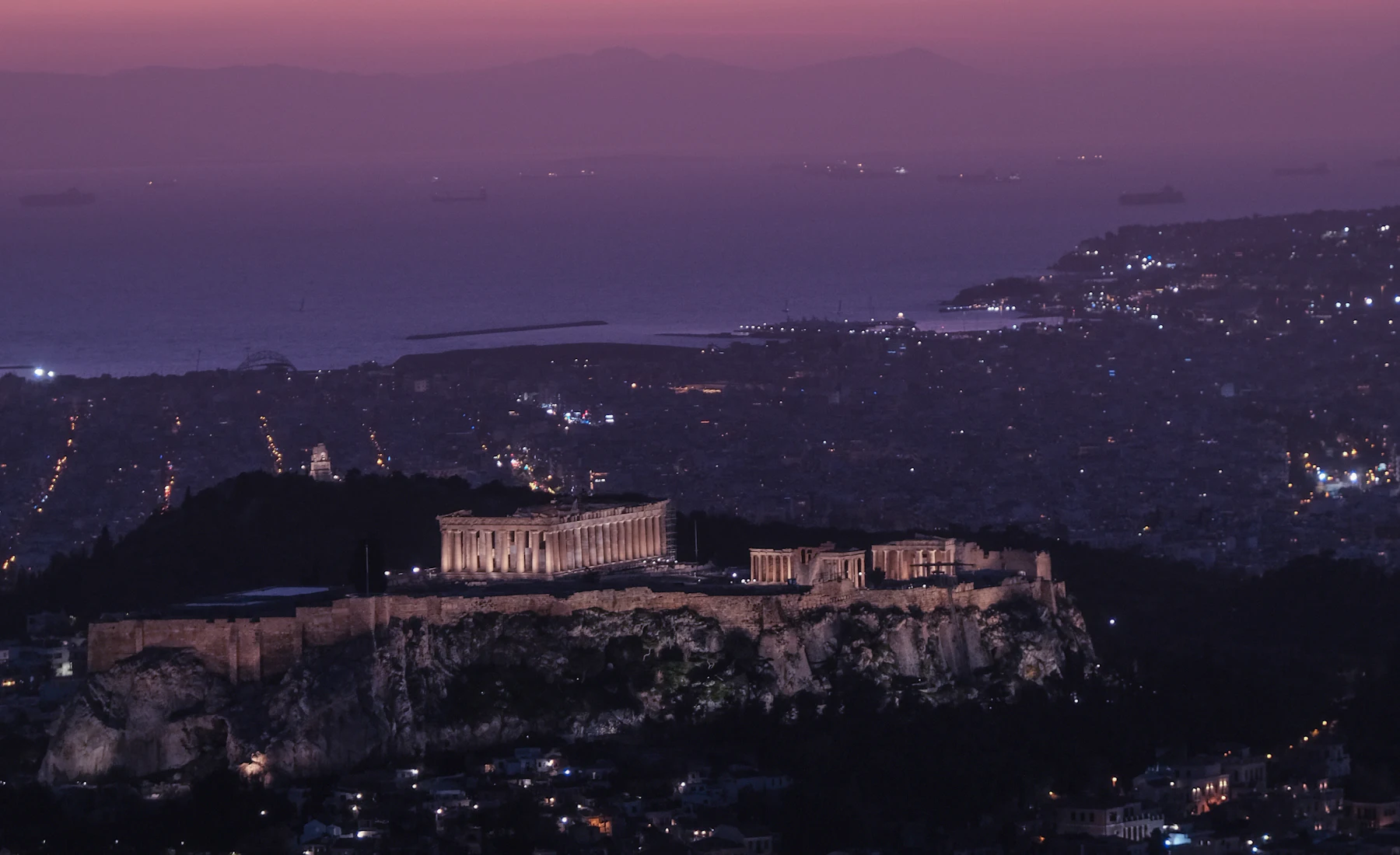 Η Ακρόπολη και η Αθήνα τη νύχτα, με τον Σαρωνικό στο βάθος